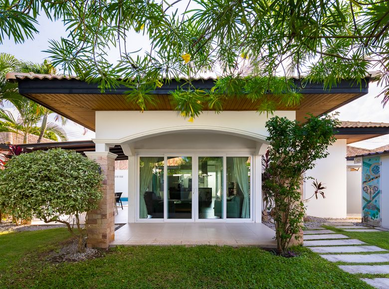 The villa in daylight, framed by its tropical garden